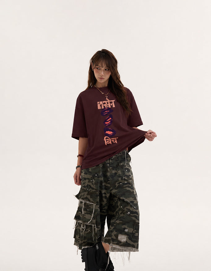 Female model wearing GUILTY PARTY red oversized Insane B!tch graphic t-shirt with abstract Hindi typography and lip print