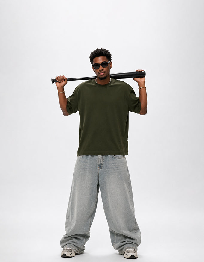 Male model wearing GUILTY PARTY olive green oversized graphic t-shirt with white back typography