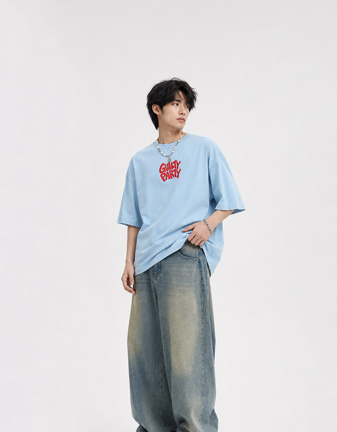 Male model wearing GUILTY PARTY baby blue oversized tee with red front chest logo in studio shoot