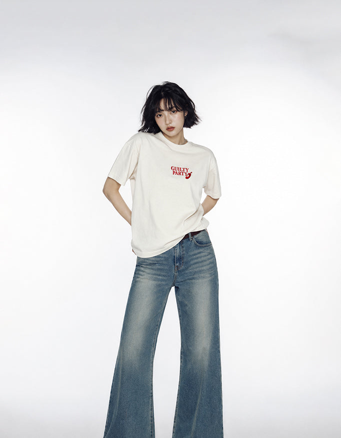 Female model wearing GUILTY PARTY Beige oversized tee with small red front logo