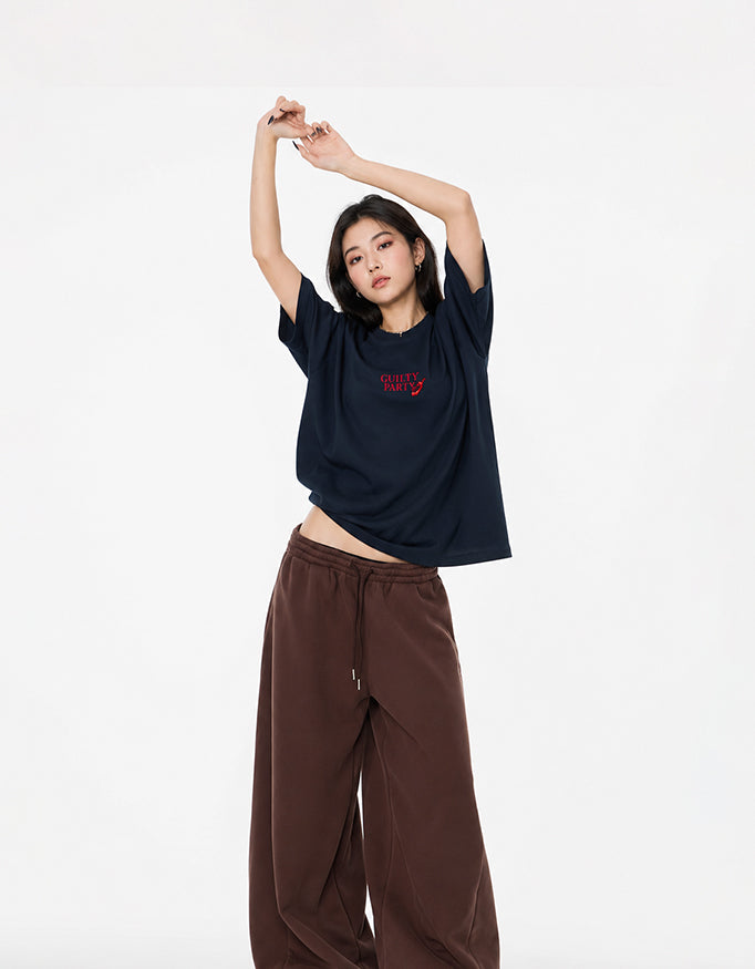 Female model wearing GUILTY PARTY navy blue oversized tee with small red front logo