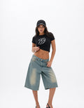 Female model wearing GUILTY PARTY black baby tee with chrome spiked front graphic in studio shoot