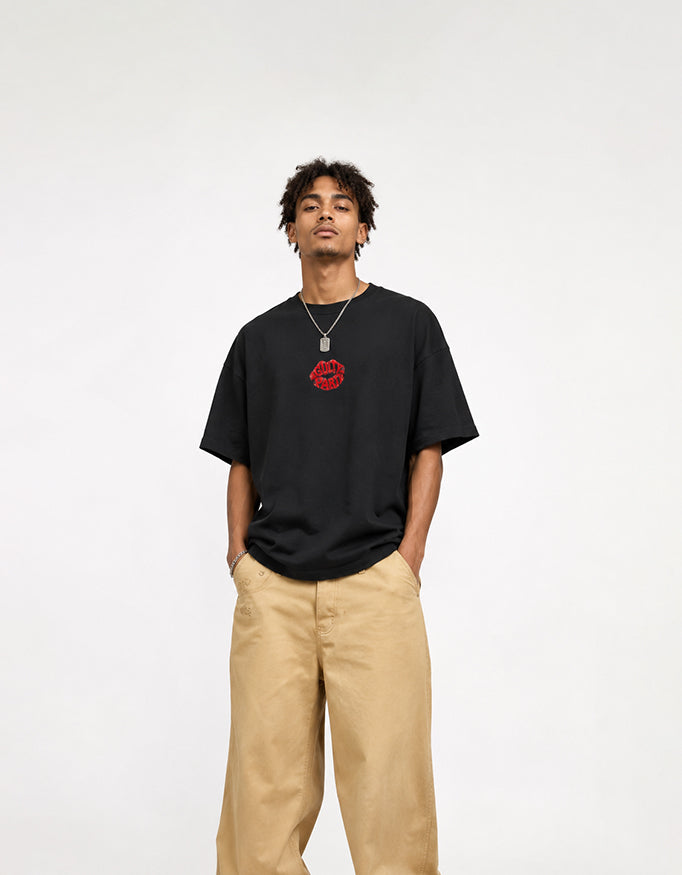 Male model wearing GUILTY PARTY black oversized tee with small red front chest logo in studio shoot