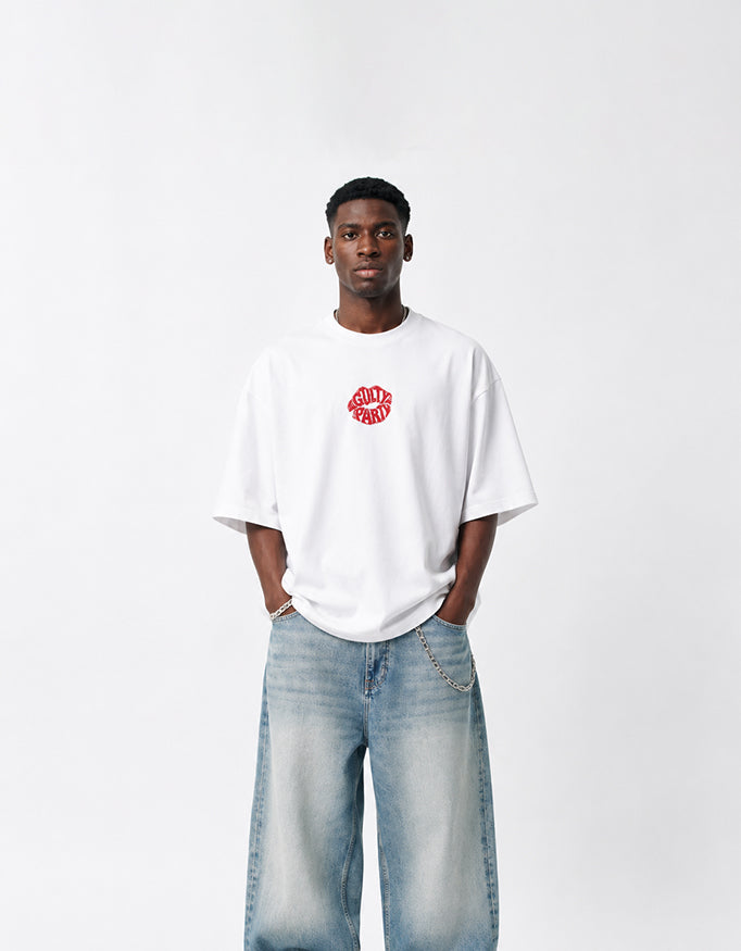 Male model wearing GUILTY PARTY white oversized tee with small red front chest logo in studio shoot