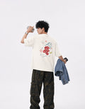 Back view of GUILTY PARTY off white oversized tee with colorful graphic back print in studio shoot saying vodka cranberry