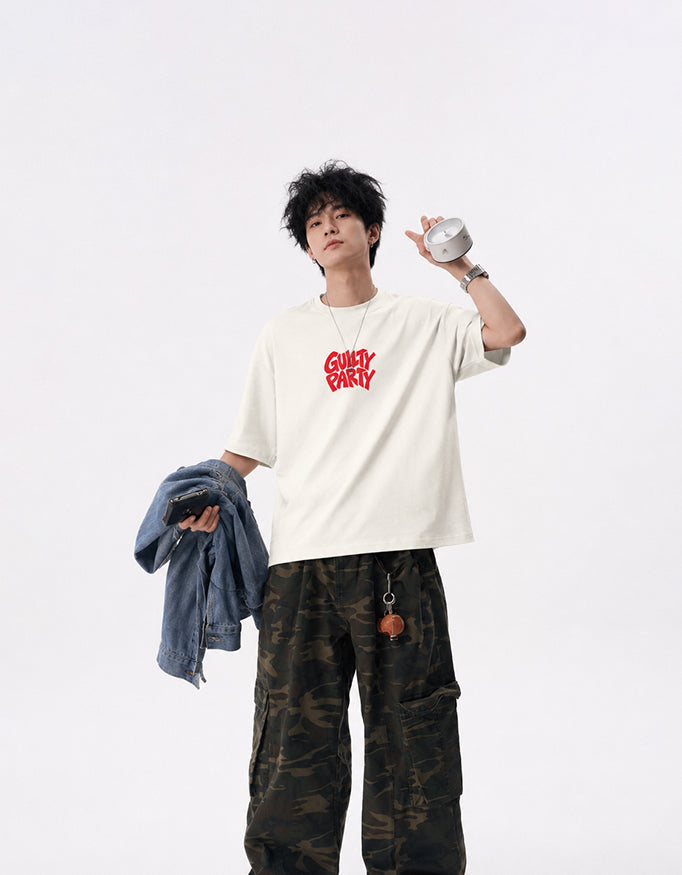 Male model wearing GUILTY PARTY off white oversized tee with red front chest logo in studio shoot