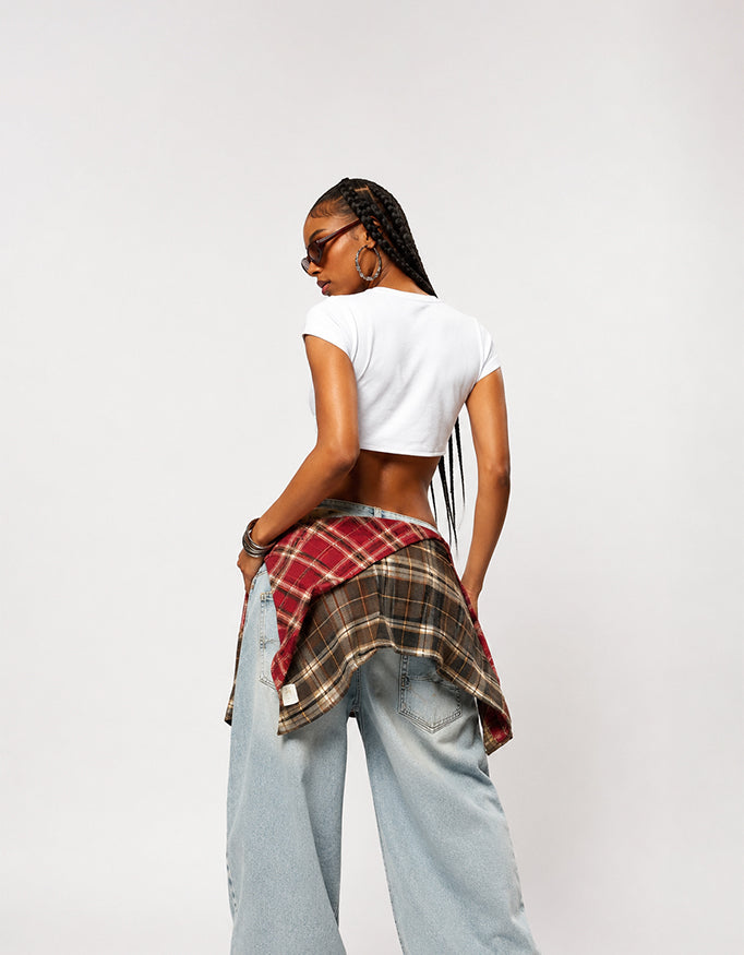 Female model wearing GUILTY PARTY SPEAK white graphic baby tee with baggy jeans in a studio streetwear shoot