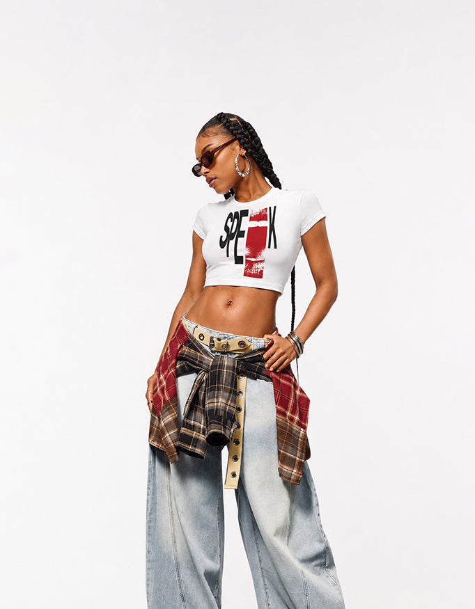 Female model wearing GUILTY PARTY SPEAK white graphic baby tee with baggy jeans in a studio streetwear shoot